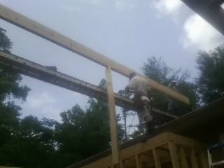 Carpenter setting a ridge beam over a new addition frame — Ice Dam Removal by Roofing Brothers in Gilford