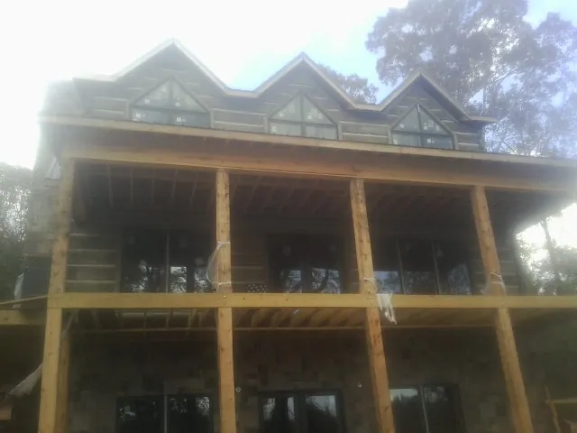 Dormers and porch framing on a large log home under construction — Roof Coating work by our crew in Gilford