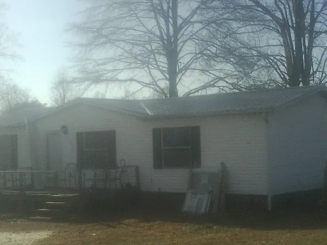 New metal roof on a white painted brick home on a foggy morning in Gilford