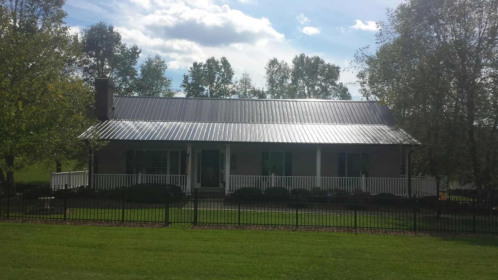 Gray metal roof on a brick ranch with a full width front porch — Gutter Guard Installation work by our crew in Gilford
