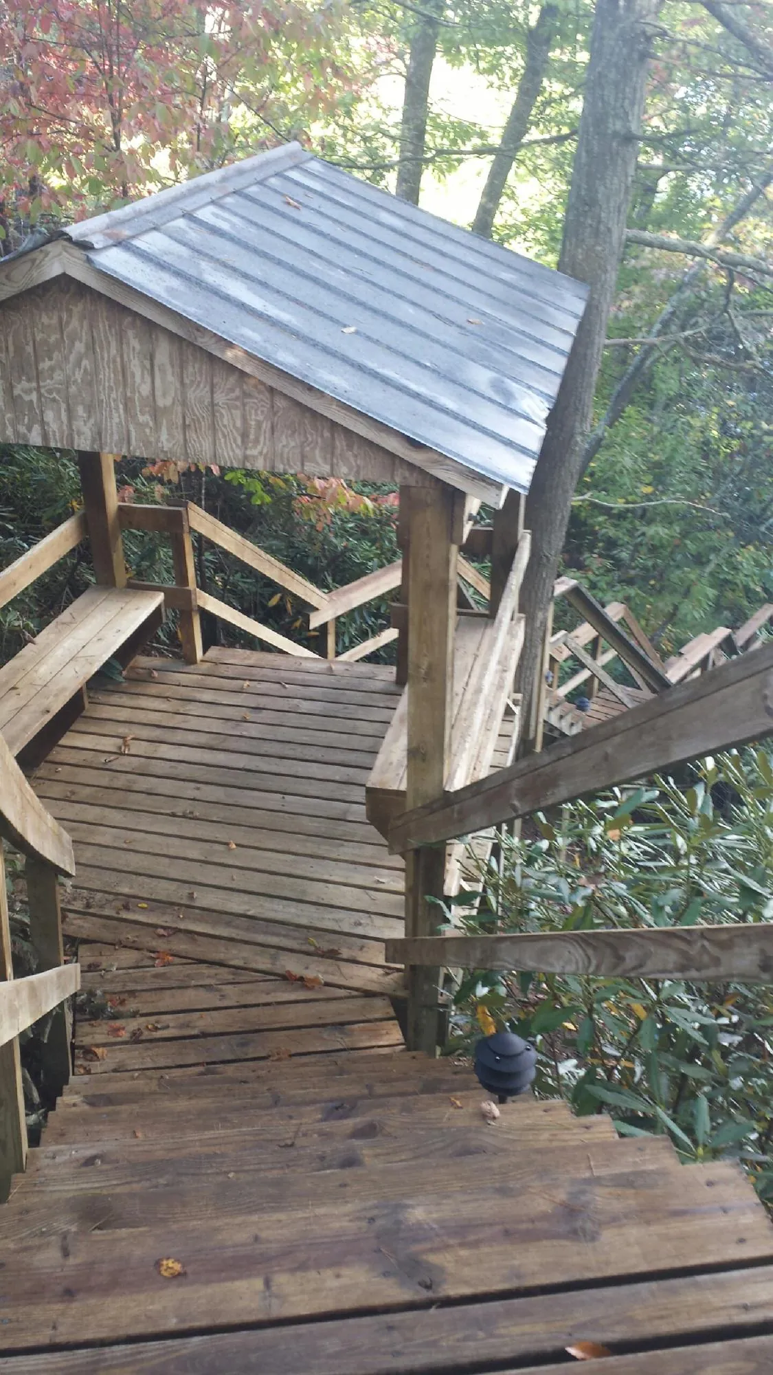 Metal roofed shelter over wooden steps on a wooded walkway — Skylight Repair & Installation work by our crew in Gilford