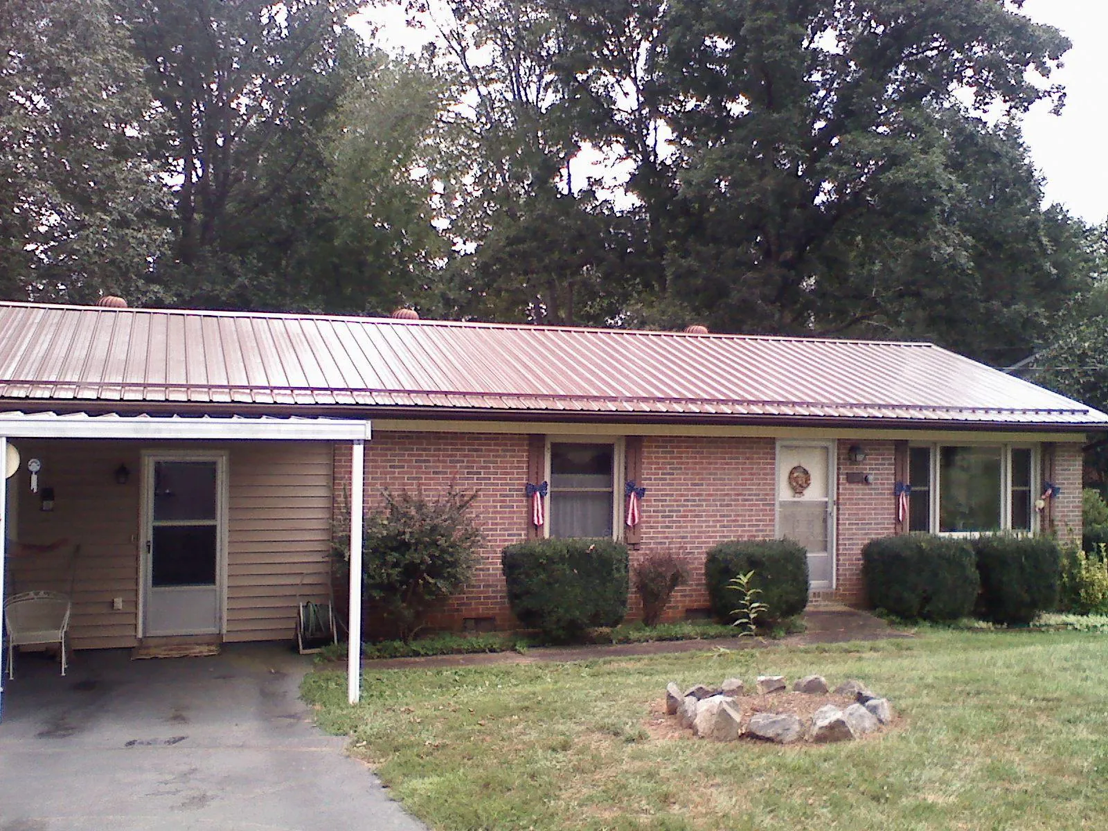 Bronze metal roof and carport on a brick ranch home — Roof Repair work by our crew in Gilford