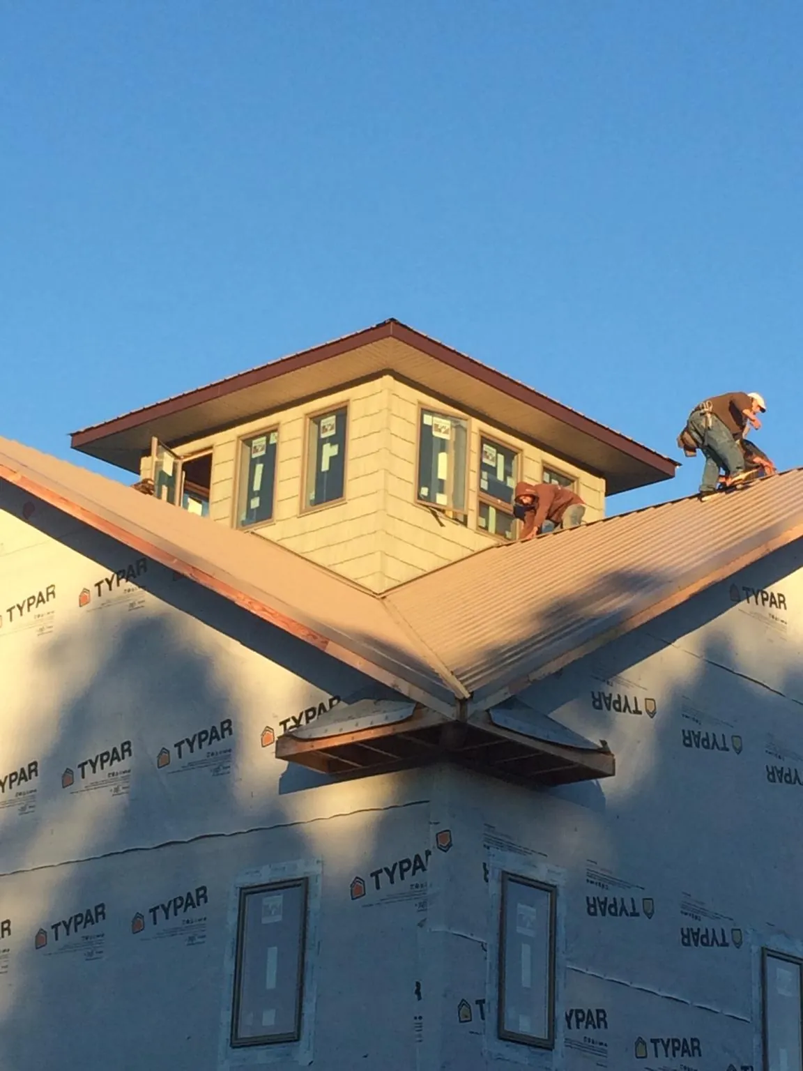 Roofers working around a rooftop cupola on a new metal roof at sunset — Roof Waterproofing in Gilford by Roofing Brothers